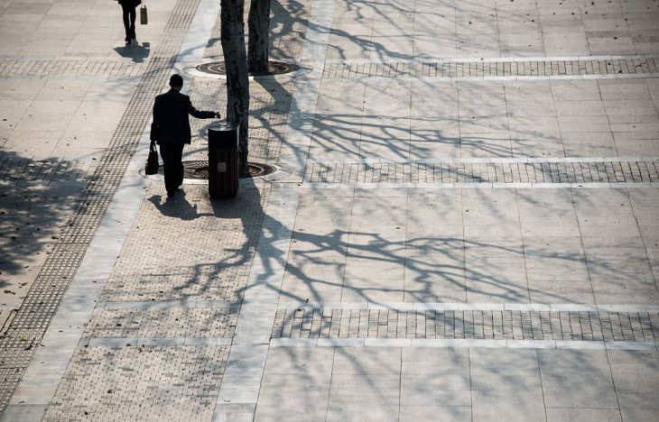 2016年4月、上海の金融街で、路上のごみ箱にゴミを捨てる通勤中の男性(JOHANNES EISELE/AFP/Getty Images)