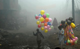2016年12月、パキスタン北部ラホールで、濃いスモッグに見舞われる街の中を歩く風船売りの少年（ARIF ALI/AFP/Getty Images）