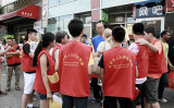 2013年8月、在米中国人の多い米ニューヨーク市フラッシング地区で、共産党主導の反カルト運動のゼッケンを着てアンチ法輪功のビラを撒いていた中国系の若年者たち。大紀元記者を囲み話している（大紀元）