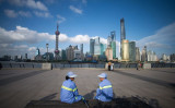 人権弁護士は大紀元の取材に対して「中国の民衆が目覚めつつある」と語った。上海タワー近くで休憩する清掃作業員たち（JOHANNES EISELE/AFP/Getty Images）
