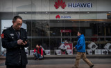 2019年1月、北京のファーウェイ（華為科技、HUAWEI）店舗前でスマートフォンを操作する男性（Kevin Frayer/Getty Images）