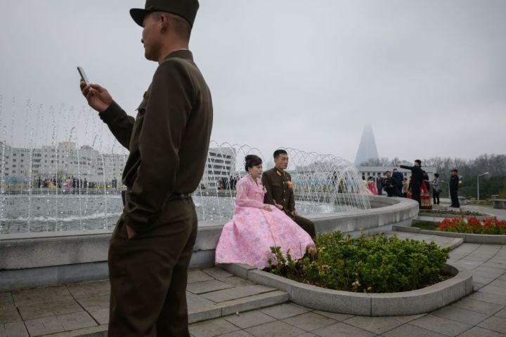 中国通信技術大手ファーウェイは、北朝鮮の厳格な情報システム構築に協力しているという。米シンクタンク傘下の北朝鮮情報サイト・38ノースが7月22日報じた。写真は2019年4月、平壌市内で、記念撮影するカップルと携帯電話を操作する若い兵士（GettyImages）