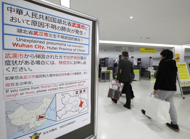 成田空港で新型コロナウイルスについて注意喚起を行っている（STR/JIJI PRESS/AFP via Getty Images）