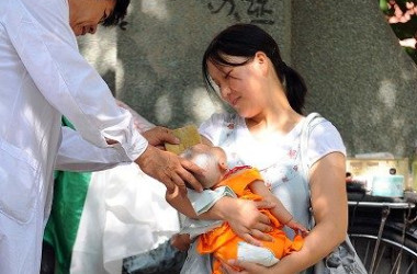 写真は中国北京市の路上で赤ちゃんを抱く母親の姿(AFP)