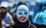2018年7月5日、イスタンブールの中国領事館前で、中国のイスラム人迫害を非難するデモ参加者。この人のマスクは東トルキスタン （一部のウイグル人分離主義者は新疆ウイグル自治区をこう呼ぶ） の旗のデザインで、口は中国国旗の色をした手で覆われている（OZAN KOSE/AFP/Getty Images）
