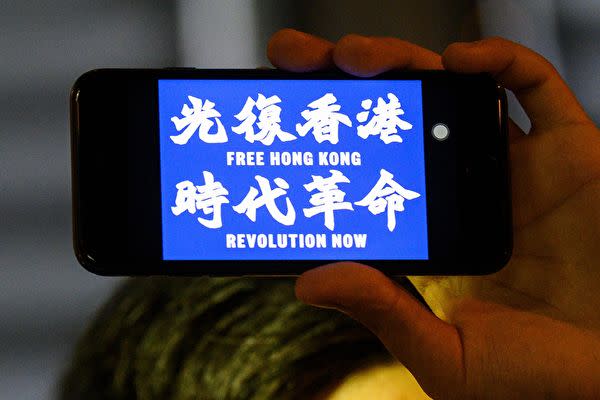2019年8月23日、「光復香港、時代革命（香港を取り戻せ、時代の革命だ）」と書かれた携帯を手に持つ香港の抗議者（ANTHONY WALLACE/AFP/Getty Images）