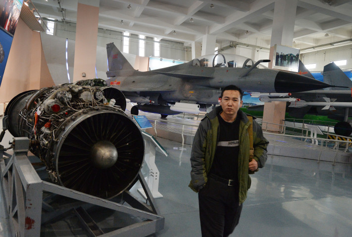 2013年12月4日、北京の人民解放軍航空博物館に展示されている中国製のJ-10戦闘機の前を歩く男性。（MARK RALSTON/AFP via Getty Images）