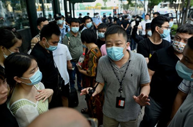 2021年9月15日、中国深セン市の恒大集団本社ビル前で集まる抗議者に話しかける私服警官(NOEL CELIS/AFP via Getty Images)
