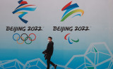 北京国家遊泳中心（北京国家水泳センター）にある2022年北京冬季オリンピックのロゴの前を歩く中国人男性＝2021年4月9日（Lintao Zhang/Getty Images）
