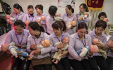 中国・北京の大学で開催された乳母の資格を取るための養成コースで、プラスチック製の赤ちゃんを抱き、トレーニングを受ける女性たち（Kevin Frayer/Getty Images）
