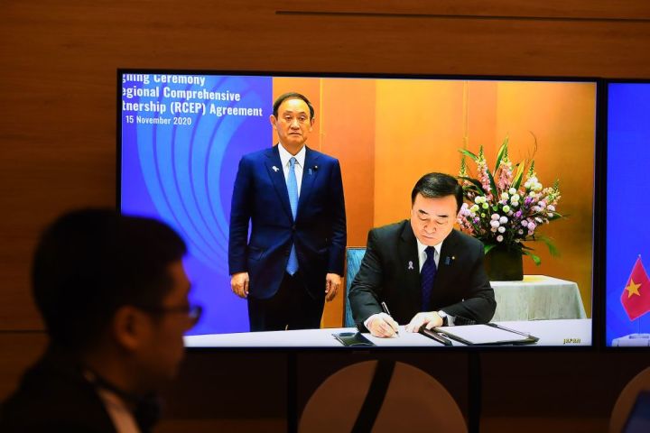 菅首相（当時）立ち会いの下、RCEP協定に署名する梶山経産相（当時）。2020年11月15日撮影 （Photo by NHAC NGUYEN/AFP via Getty Images）