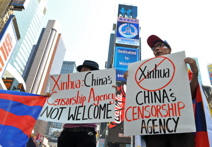 2011年8月1日、ニューヨークのタイムズ・スクエアに表示された中国新華社通信の電子掲示板の下で抗議するチベットの学生たち（Stan Honda/AFP via Getty Images）