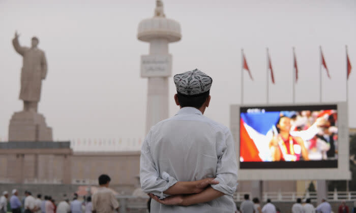 2008年北京五輪の開会式が映し出される大型スクリーンを見つめるウイグル人（Peter Parks/AFP via Getty Images）