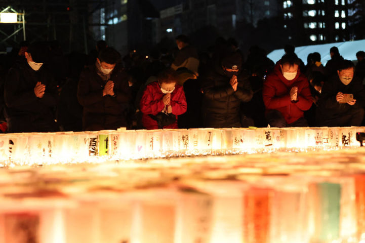 神戸市で阪神淡路大震災の犠牲者に祈りを捧げる人々。1月17日撮影（Photo by STR/JIJI PRESS/AFP via Getty Images）