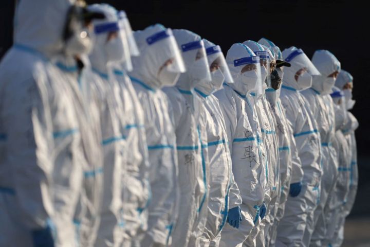 1月11日、中国北部・陝西省の西安にあるショッピングモールの外で、個人防護具（PPE）を着用したスタッフが消毒剤を散布する準備をしている （Photo by STR/AFP via Getty Images）