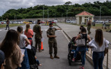 2021年4月28日、沖縄県宜野湾市のキャンプ・フォスターで、ウイルスワクチンの接種を受けるために列を作っている軍人や家族を指示する米海軍衛生兵（Carl Court/Getty Images）