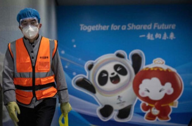 北京の清河駅前で、2022年北京冬季オリンピックの宣伝ボードの前を歩く清掃員 （Carl Court/Getty Images）