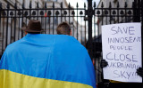 2022年2月25日、ロンドン中心部のダウニング街ゲート前で行われたロシアのウクライナ侵攻に抗議する集会で、ウクライナ国旗に包まれた人々（TOLGA AKMEN/AFP via Getty Images）
